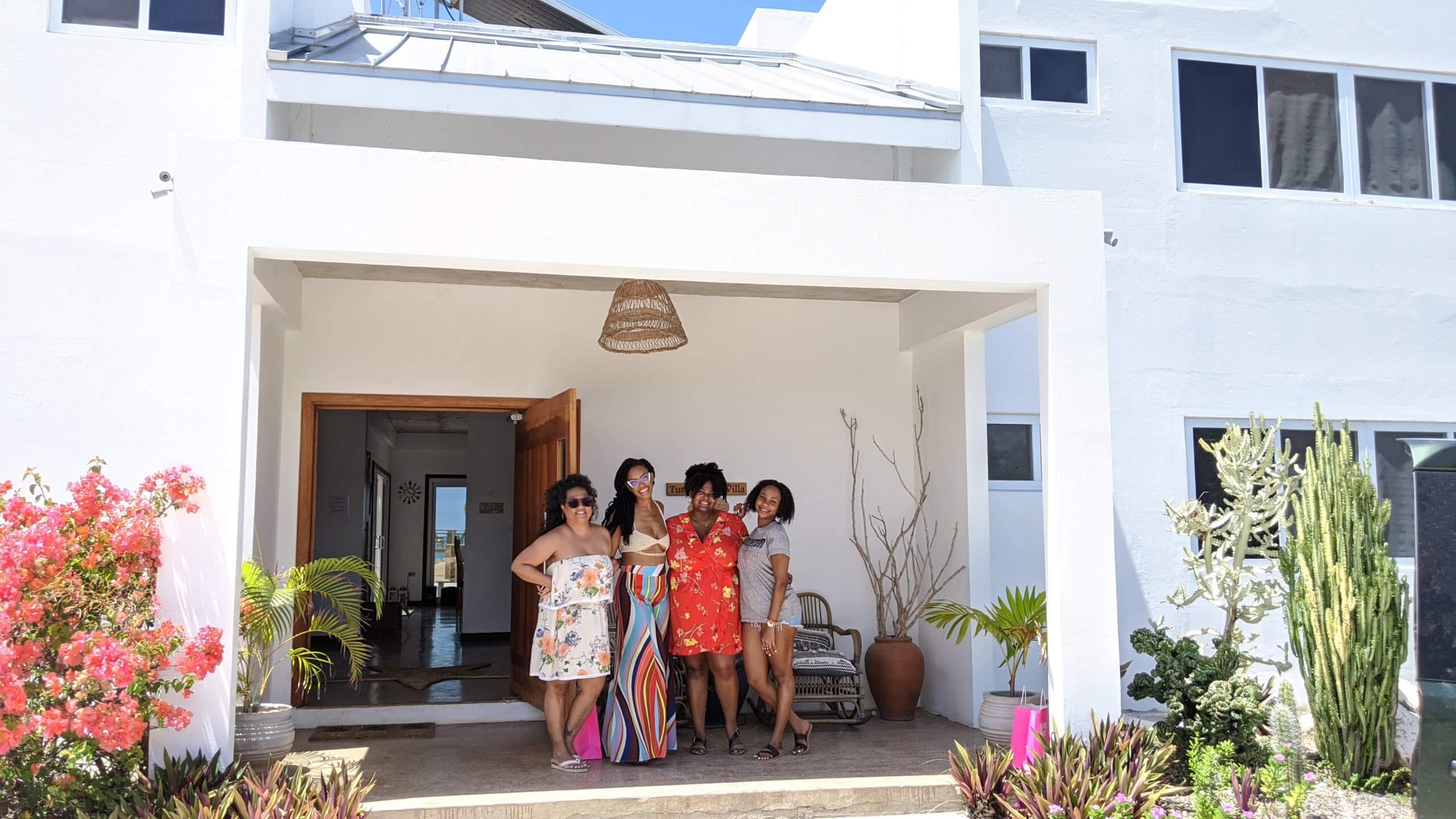 4 Jamaican women pose happily in front of the Turtles' Nest Villa in St. Elizabeth